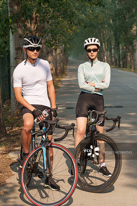 骑行的青年情侣站在树林里图片素材