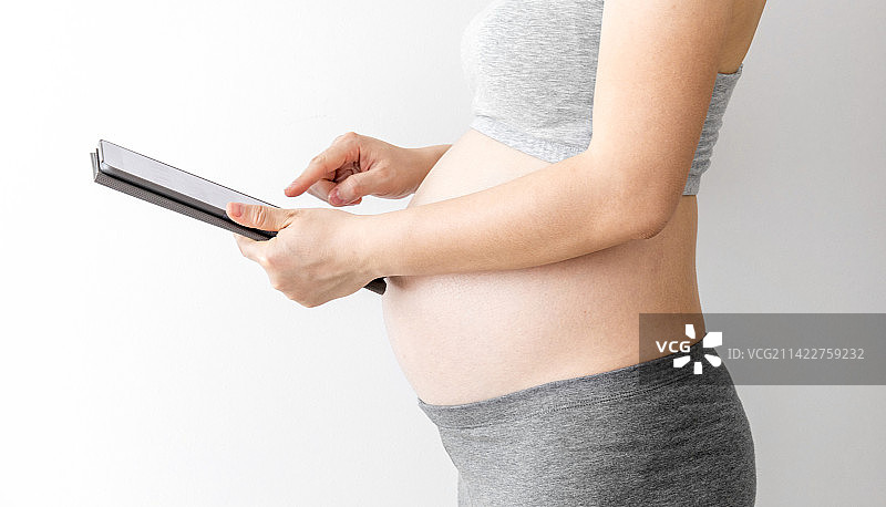 室内一位年轻孕妇在使用平板电脑图片素材