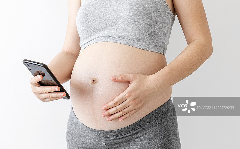 室内一名年轻孕妇在玩手机图片素材