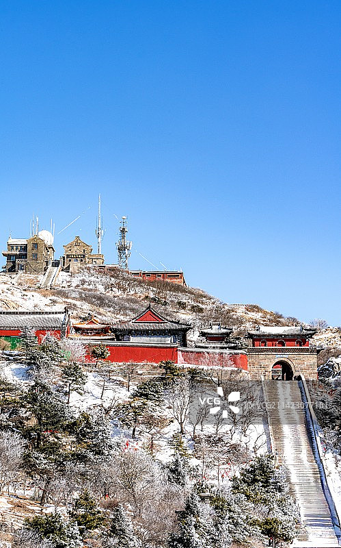 纯净蓝天与白雪背景映衬中的山东泰山风西神门碧霞祠红墙黛瓦建筑景观与日观峰气象台全景图镜头图片素材
