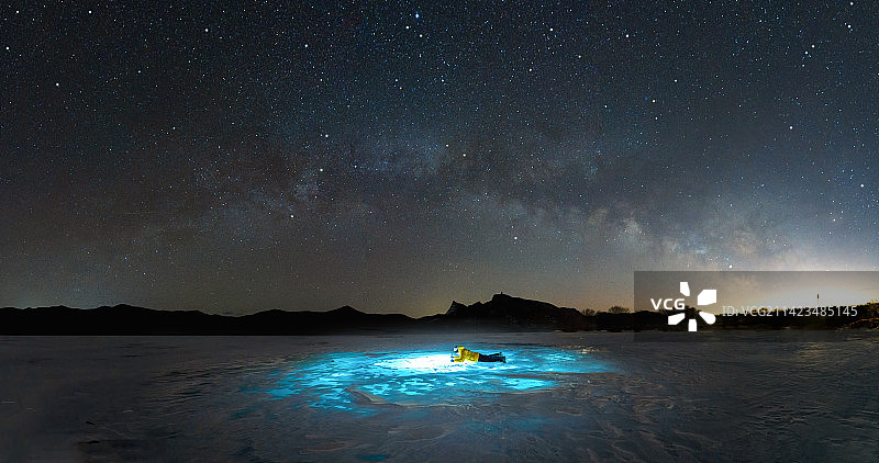 星空下得一个人用手电照射冰面图片素材