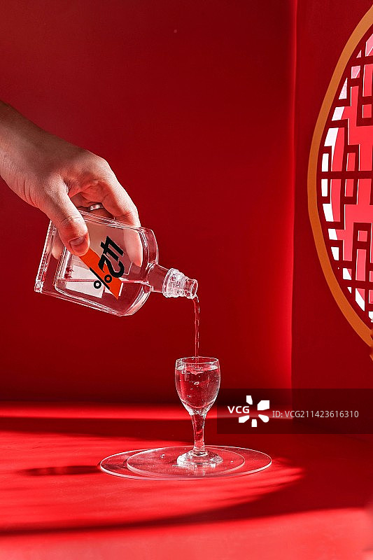 红色背景下手持酒杯的特写镜头图片素材