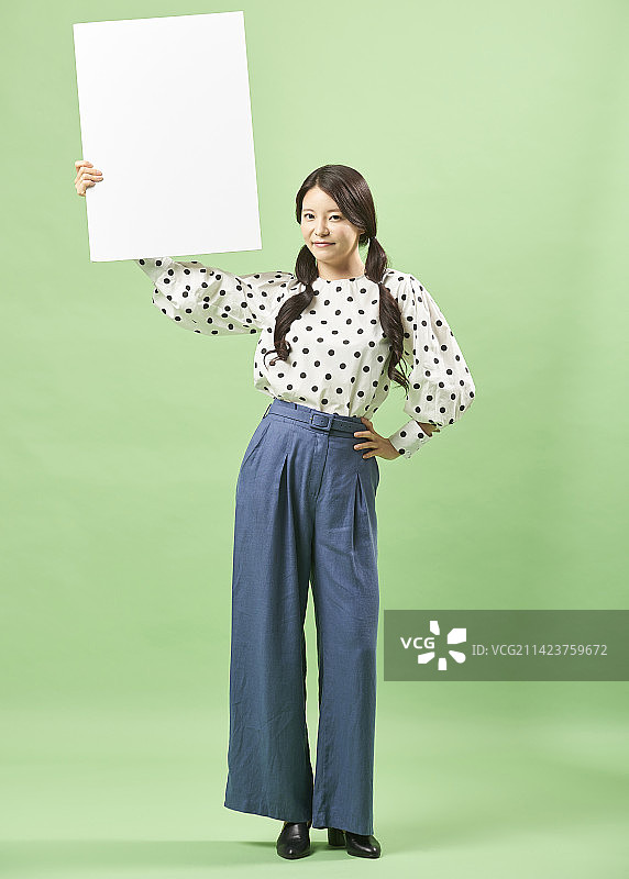 拿着白色纸张的年轻女子（影棚拍摄）图片素材