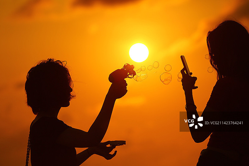 海南三亚市三亚湾夕阳中，2名女孩在游玩，乐享童趣时光。图片素材