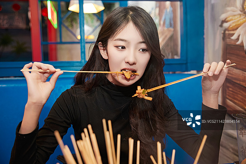 在饭馆吃成都串串的亚洲少女图片素材