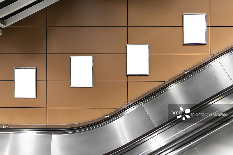 地铁站自动扶梯旁的墙上挂着空白广告牌图片素材