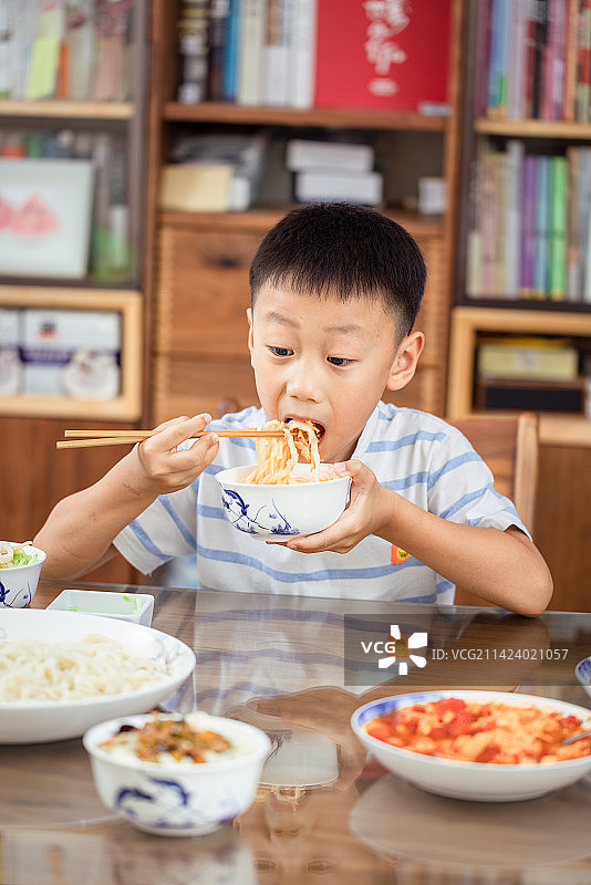 夏天在家里大口吃着打卤面的中国男孩图片素材