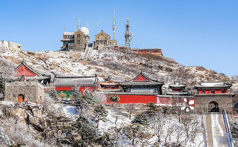 纯净蓝天白雪背景映衬中的山东泰安泰山风景区碧霞祠古建筑与日观峰气象台图片素材