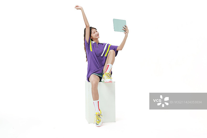 坐在木箱上玩平板电脑的美少女图片素材