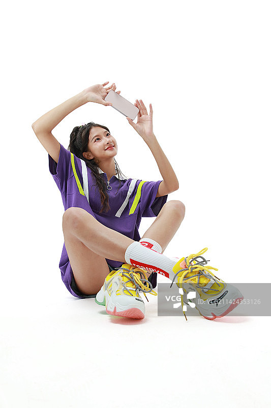 坐在地面玩手机的美少女图片素材