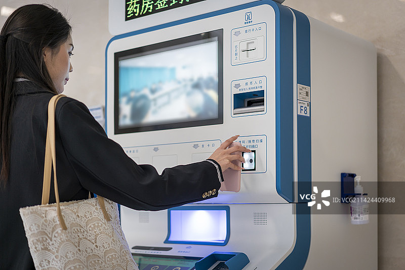 一个年轻女性在医院使用自助柜员机图片素材