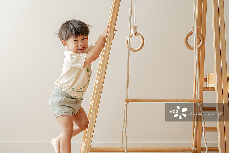 爬木框训练架梯子的小男孩图片素材