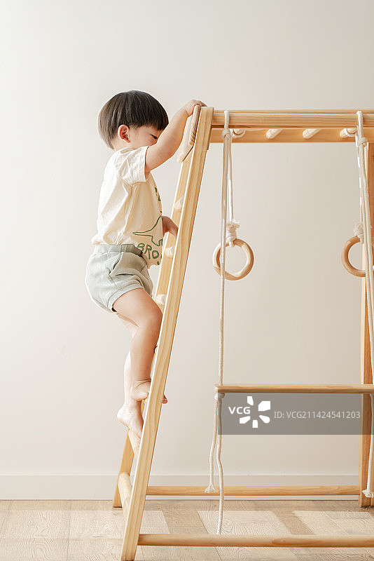 爬木框训练架梯子的小男孩图片素材