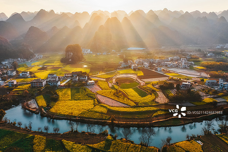 贵州省黔西南布依族苗族自治州兴义市万峰林景区上纳灰村油菜花田与喀斯特地貌春季户外风光丁达尔效航拍视角图片素材