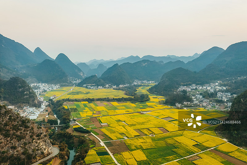 贵州省黔西南布依族苗族自治州兴义市万峰林景区下纳灰村油菜花田与喀斯特地貌春季户外日落风光航拍视角图片素材