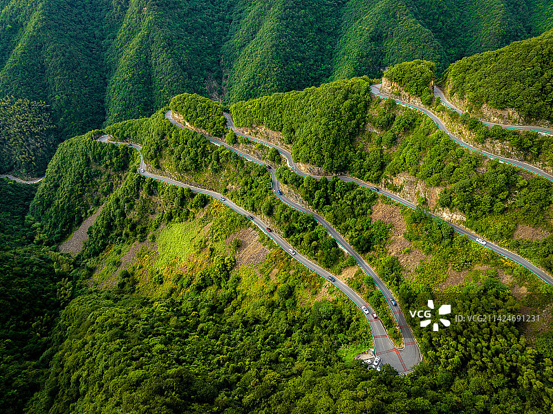 蓝天白云下竹林森林郁郁葱葱，远山如黛，蜿蜒的公路在树林里曲折穿行图片素材