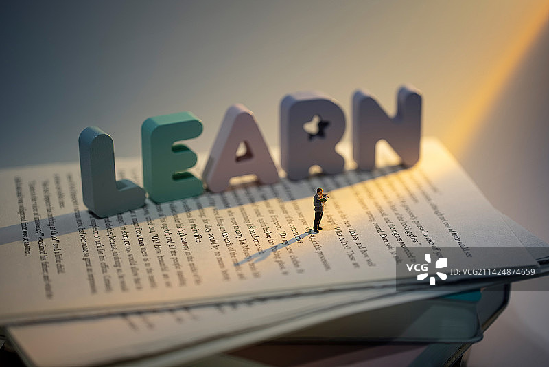 一束光照在在一摞书上和看书学习的人图片素材