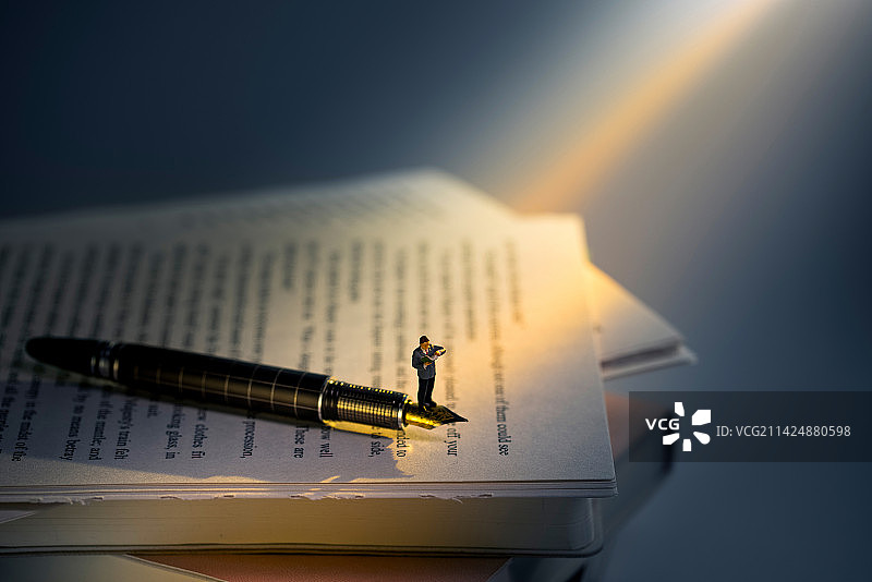 一束光照在书上站在钢笔上看书的人图片素材