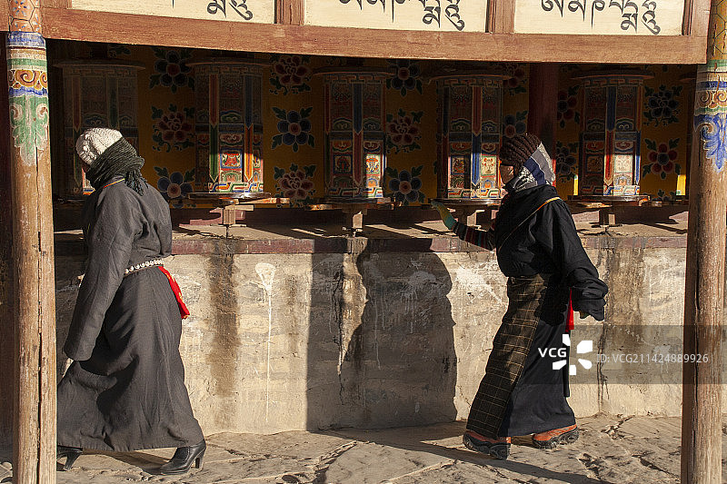 走过寺庙转经筒的两位藏族同胞图片素材