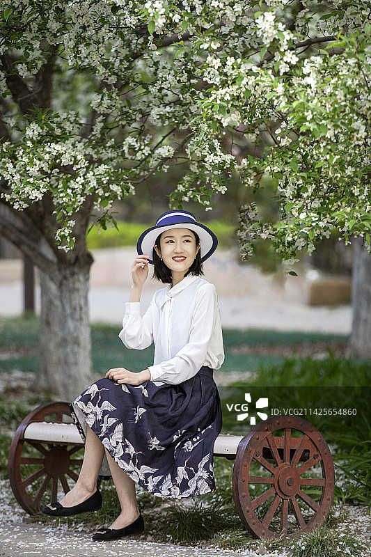 坐在公园长椅上微笑的年轻女子画像图片素材