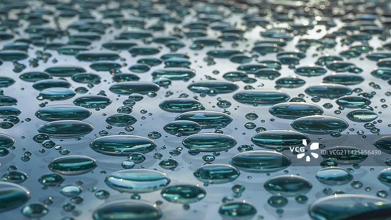 玻璃板上的雨滴在落日的映照下的影像图片素材