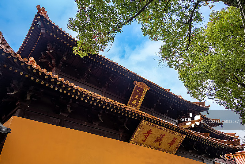 蓝天白云下苏州昆山亭林园华藏寺天王殿金黄色的围墙和牌匾掩映在绿树中图片素材