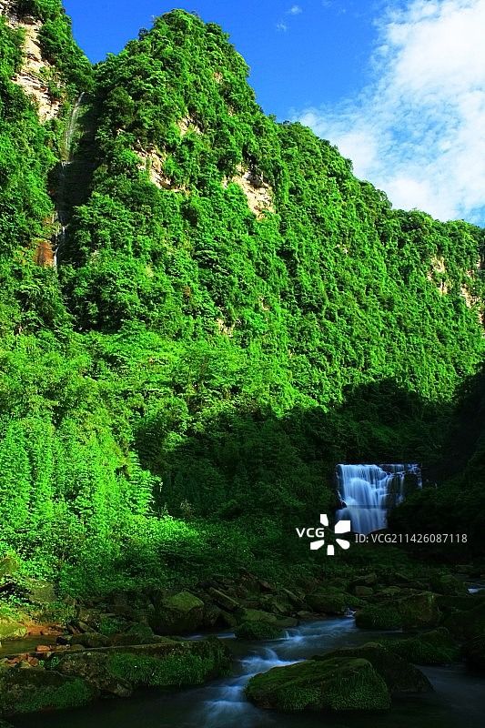 雅安市晏场镇高叠洞瀑布与溪流在蓝天白云与森林的环绕中图片素材