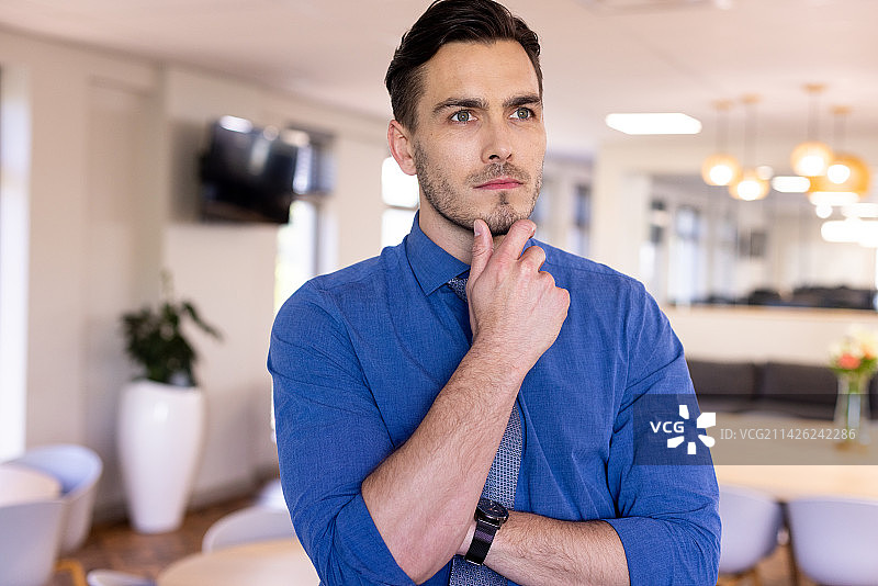 在现代办公室里思考的穿蓝色衬衫的白人商人图片素材