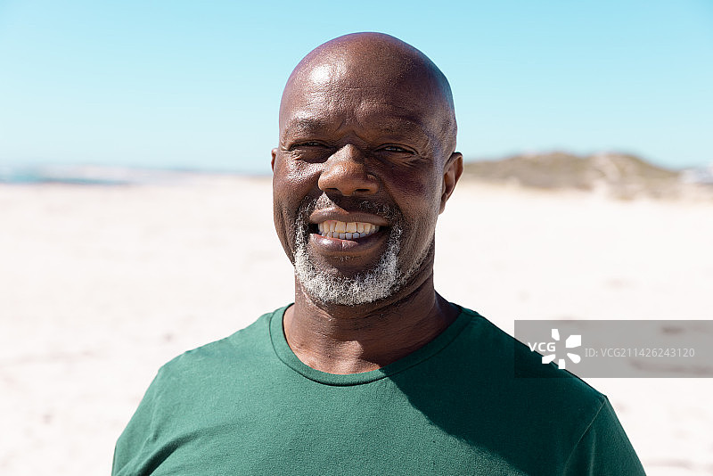 在海滩上度周末的微笑的非裔美国老年光头男性肖像图片素材
