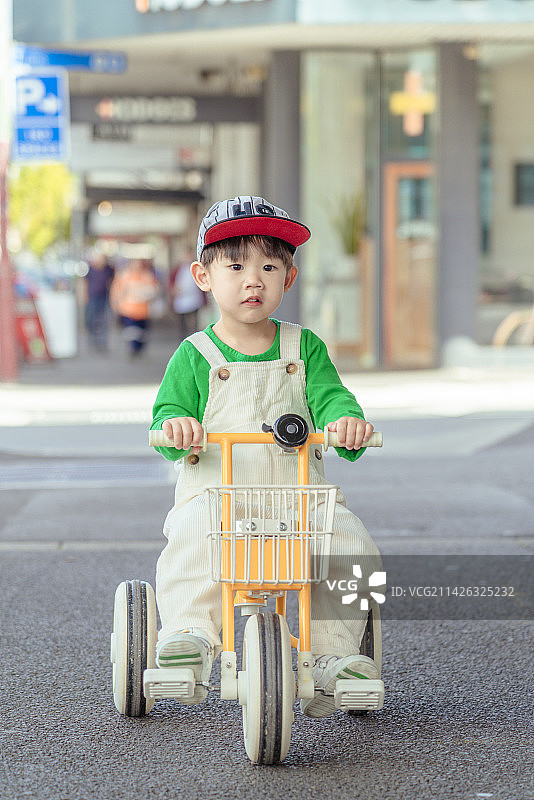 商场广场上骑童车的背带裤男孩图片素材