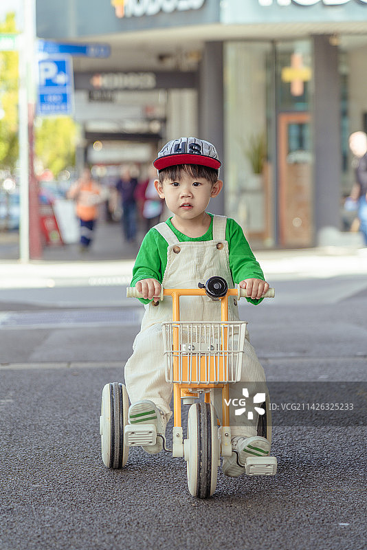 商场广场上骑童车的背带裤男孩图片素材