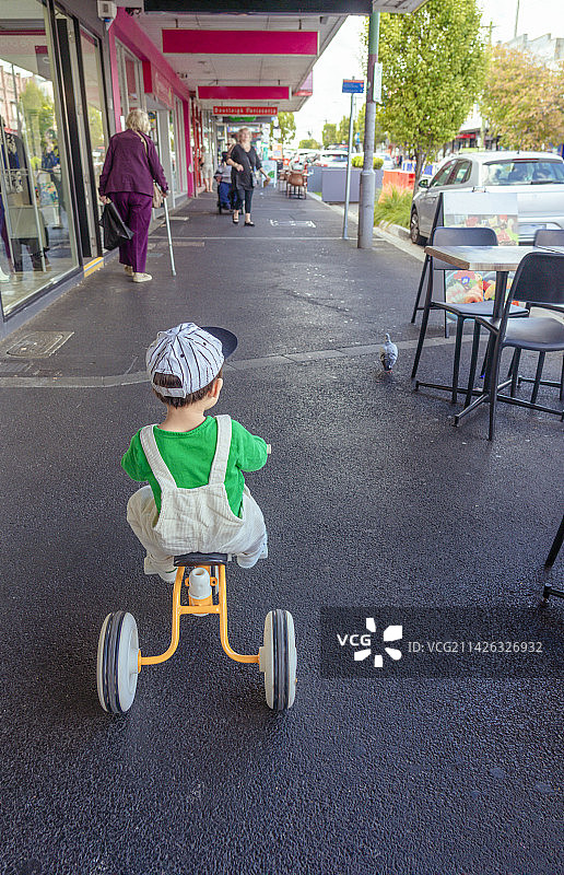商场广场上骑童车的背带裤男孩图片素材