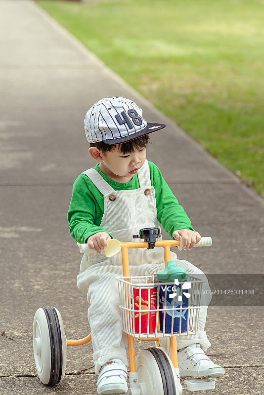 平整的小路上骑童车的棒球帽男孩图片素材