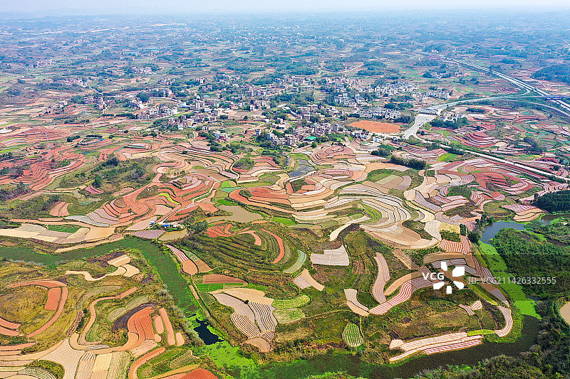 图为广西南宁田园春耕场景，层出叠见的田野生机盎然，翠绿的春苗、橙红的土地、银白的地膜萦绕交错，如织锦图片素材