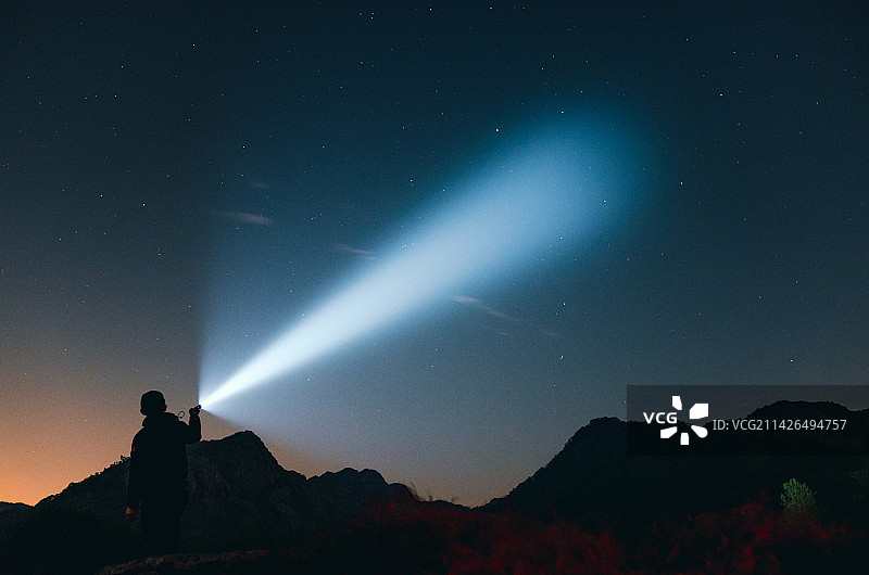 星空下拿着手电筒照射图片素材