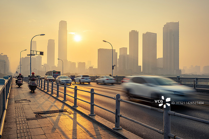 日出时分温暖的阳光照耀到长沙橘子洲大桥桥面，拉出长长的影子，桥面上的交通川流不息快速穿梭图片素材