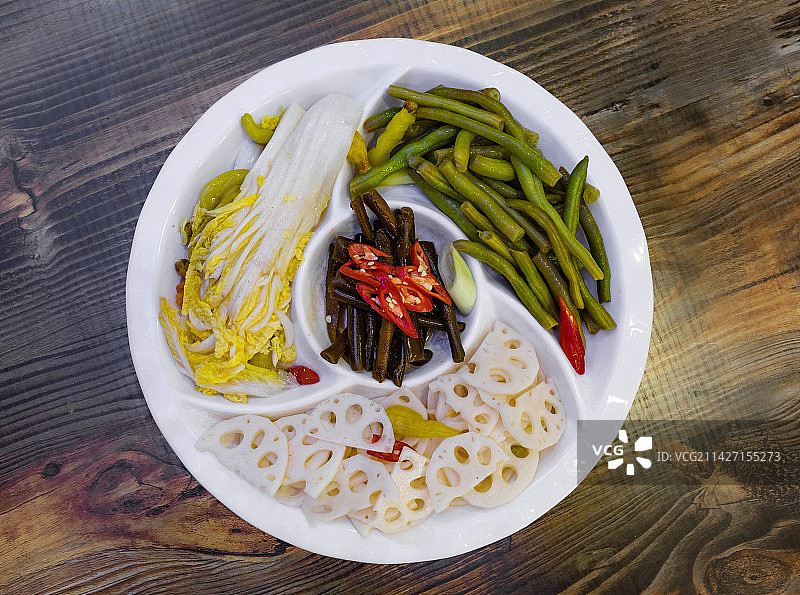 正上方俯拍木桌上白色盘子里盛着的四种不同种类的凉拌菜：娃娃菜豆角莲藕海笋图片素材