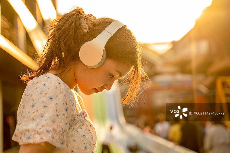 女生在夕阳下带着耳机享受音乐图片素材