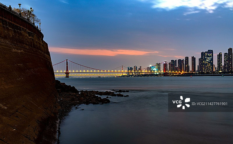 黄昏晚霞蓝天夜幕背景映衬中的中国湖北武汉长江鹦鹉洲大桥建筑景观慢门长曝光特写镜头图片素材