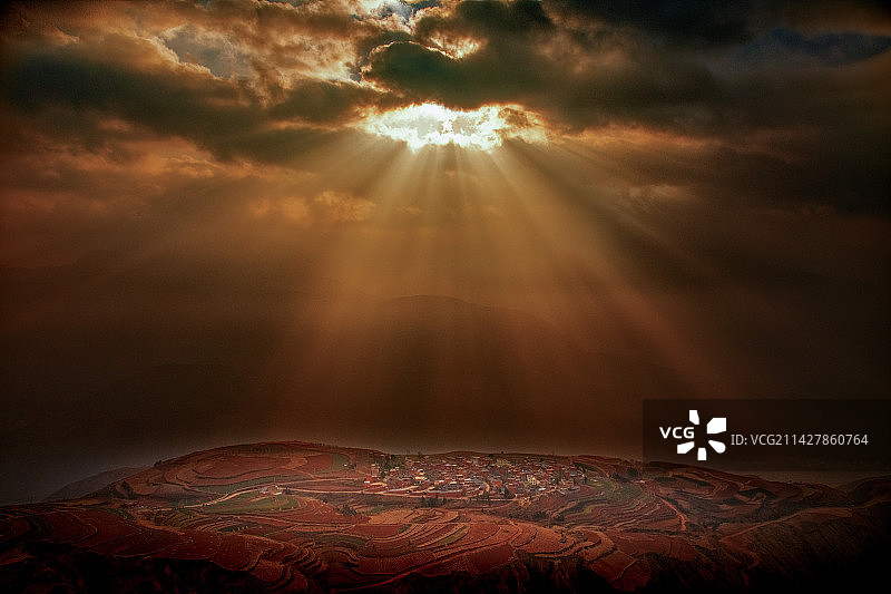 一缕阳光透过云层照射在红土地上，十分迷人。图片素材