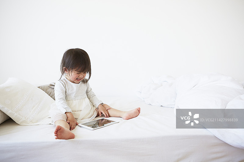 宝宝在床上穿着对襟衣，面露悲伤图片素材