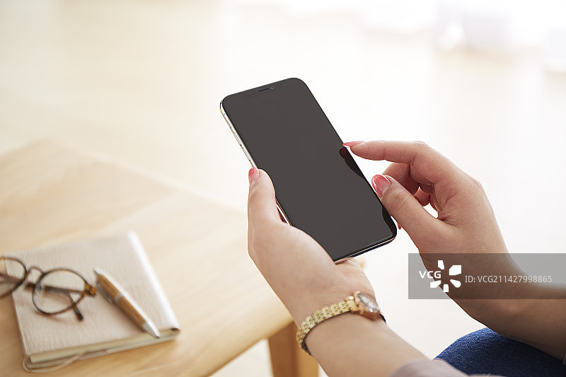 女子在客厅操作智能手机图片素材