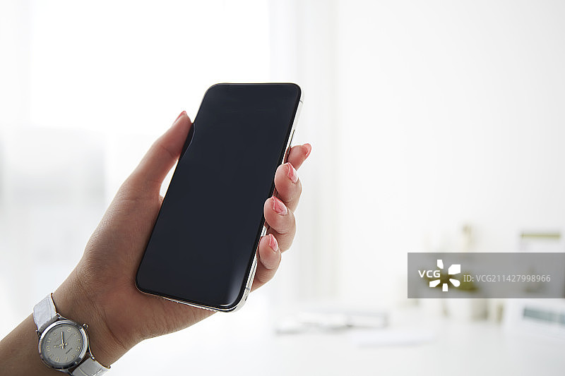 在白色桌子上使用智能手机的女人图片素材