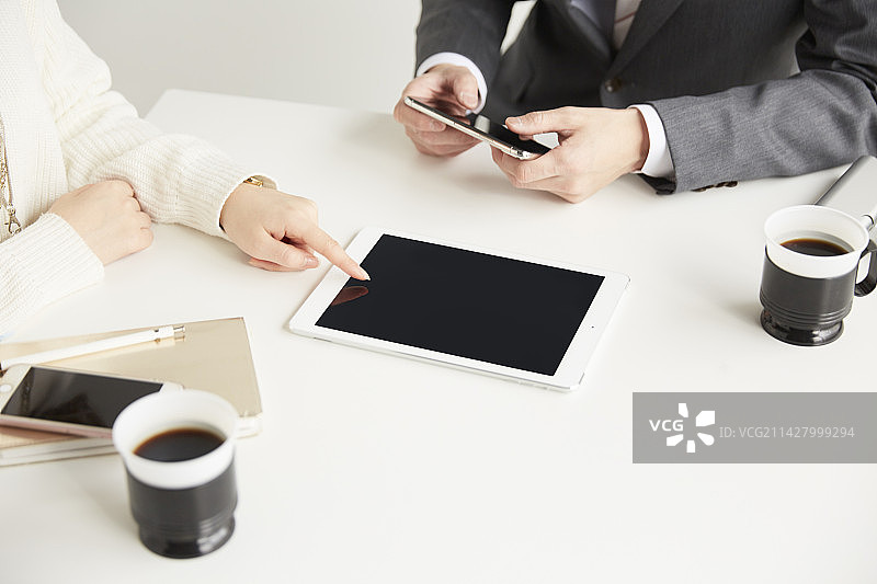 商人使用多种设备与客户洽谈业务图片素材