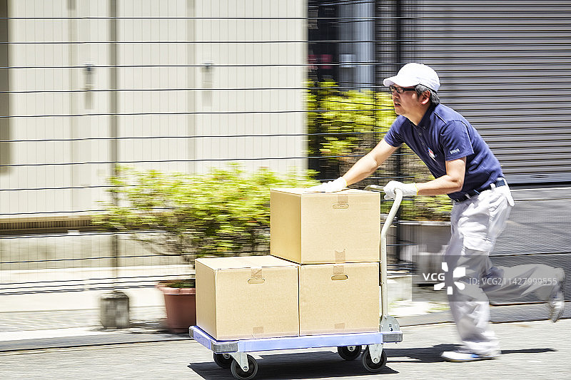 男子用手推车运送纸箱图片素材