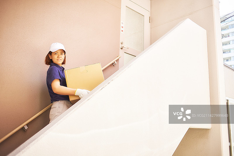 身穿工作服的女人站在公寓楼的楼梯上图片素材