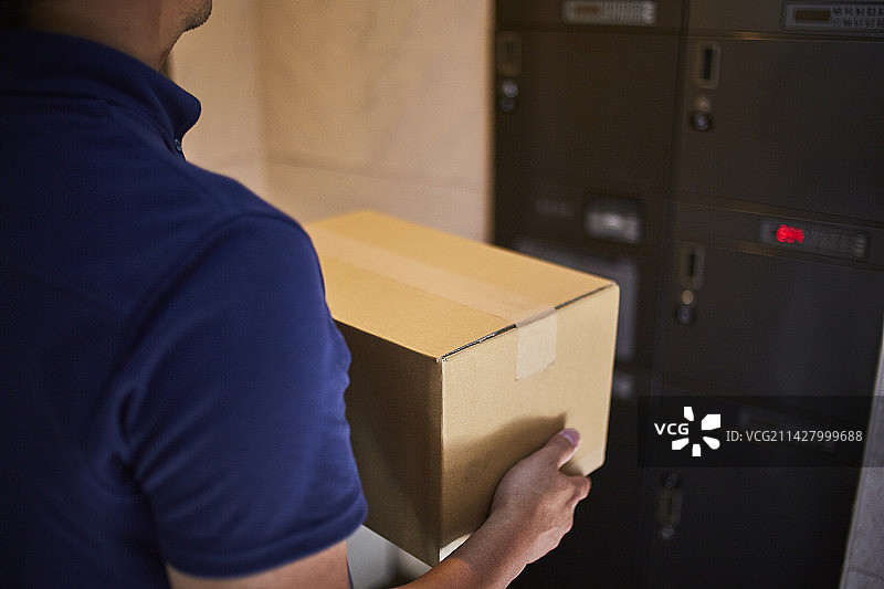 男人拿着纸箱站在快递箱前图片素材