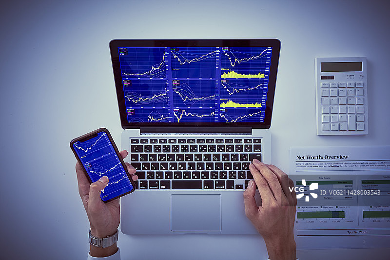 男人手持电脑和智能手机展示股票图表图片素材