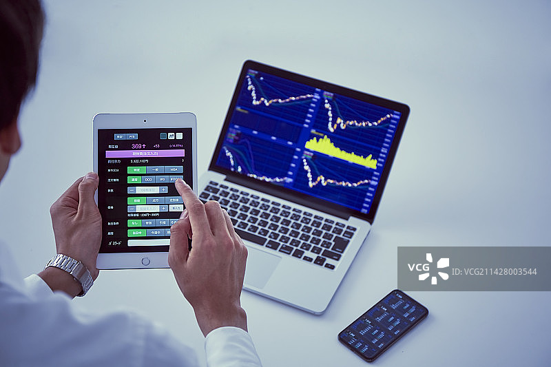 使用电脑、智能手机和平板电脑进行股票交易图片素材