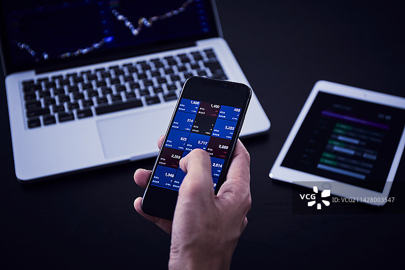 男人使用电脑、智能手机和平板电脑买卖股票图片素材